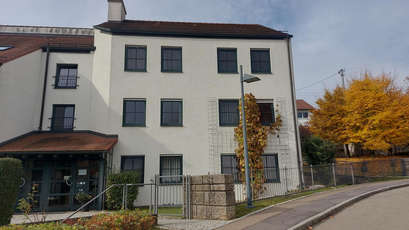 Eingang des Pfarrbüros der PG Elchingen mit Fensterfront und begrüntem Pfeiler.
