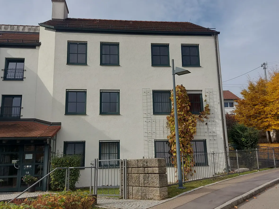 Eingang des Pfarrbüros der PG Elchingen mit Fensterfront und begrüntem Pfeiler.