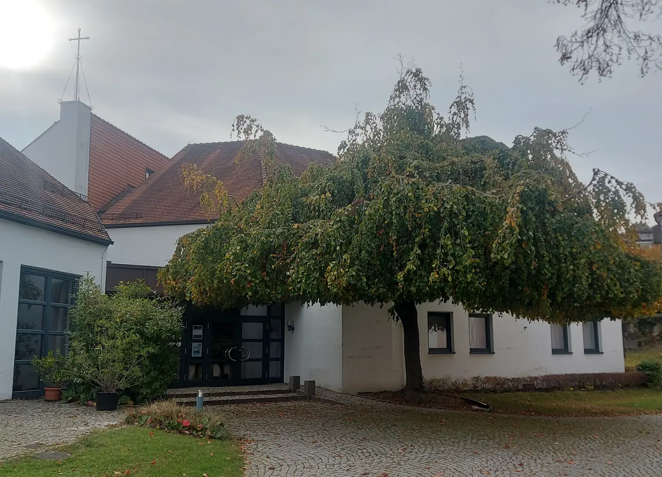 Moderne Kirche Eingangstür mit einem großen Baum auf der rechten Seite