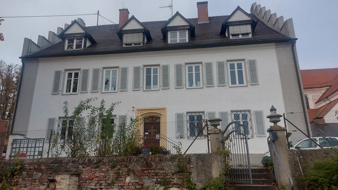 Pfarrhaus Oberelchingen Pfarrhaus Oberelchingen mit hellem Fassadenanstrich und grünen Fensterläden. Garten mit Bepflanzung.