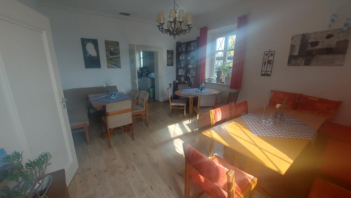 Gemütlicher Innenraum des Pfarrhauses Oberelchingen mit Tischen und Sesseln.