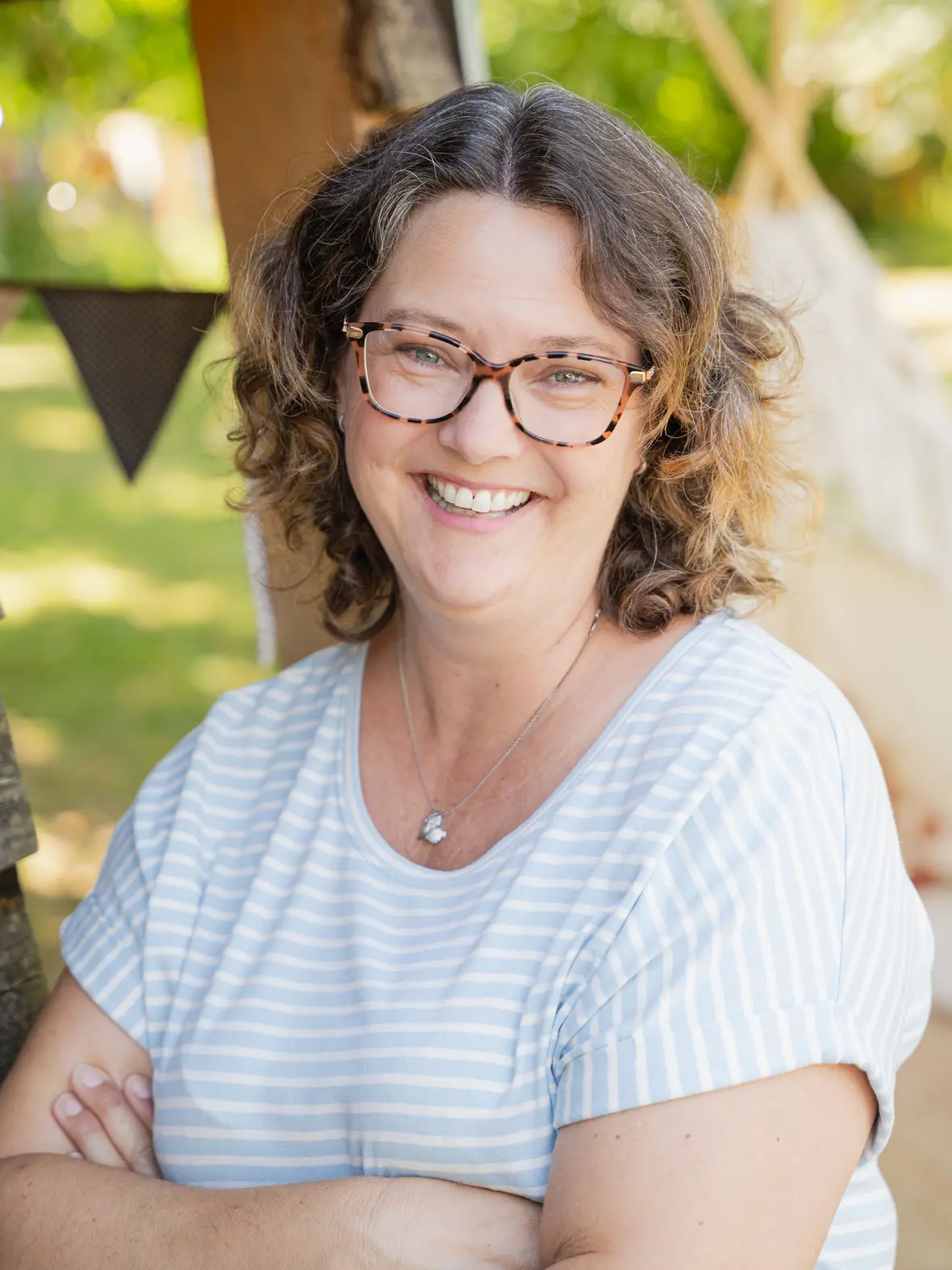 Jenny Beck-Balkheimer Jenny Beck-Balkheimer lächelt in einem Garten, umgeben von Natur und Dekorationen.