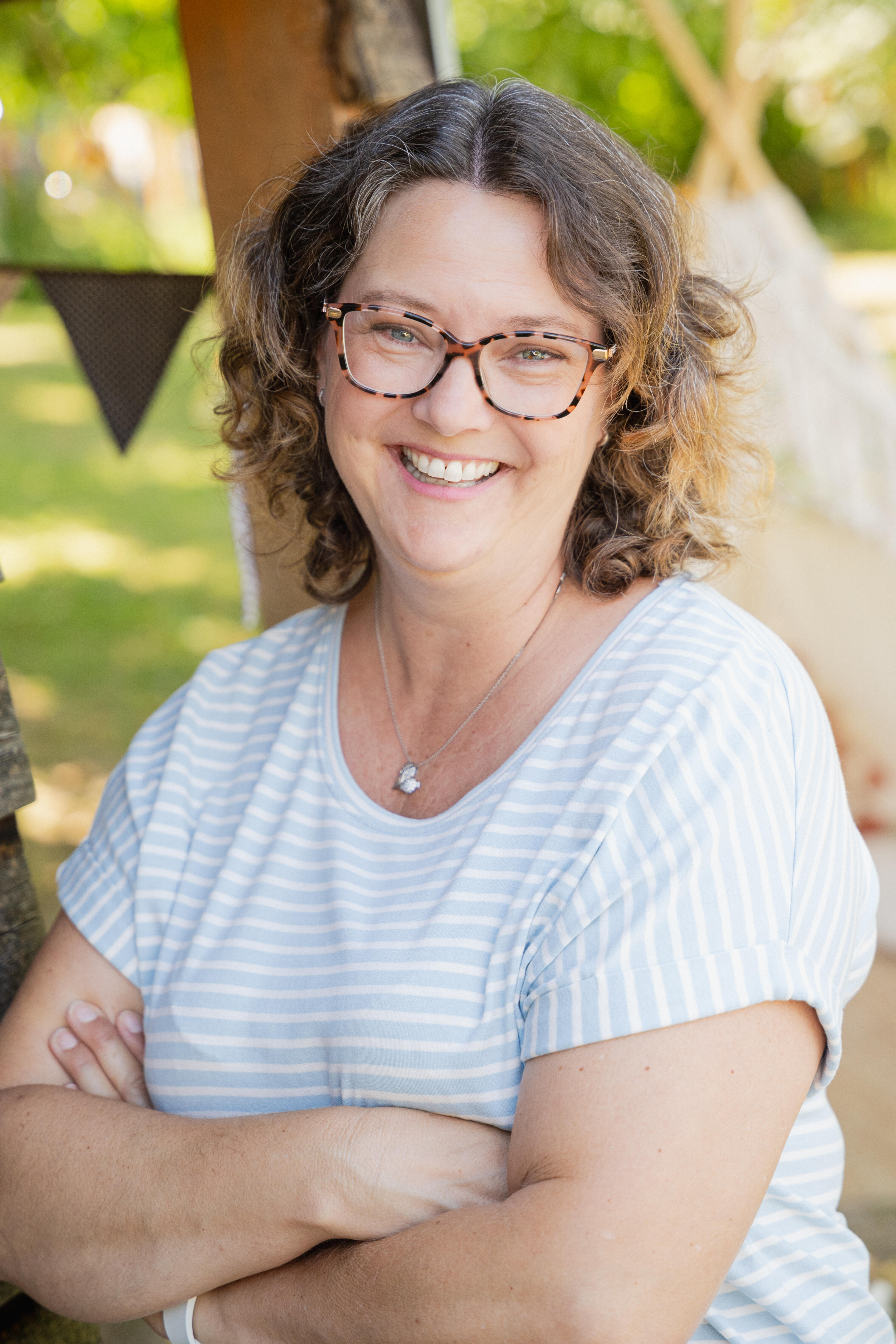 Jenny Beck-Balkheimer Jenny Beck-Balkheimer lächelt in einem Garten, umgeben von Natur und Dekorationen.