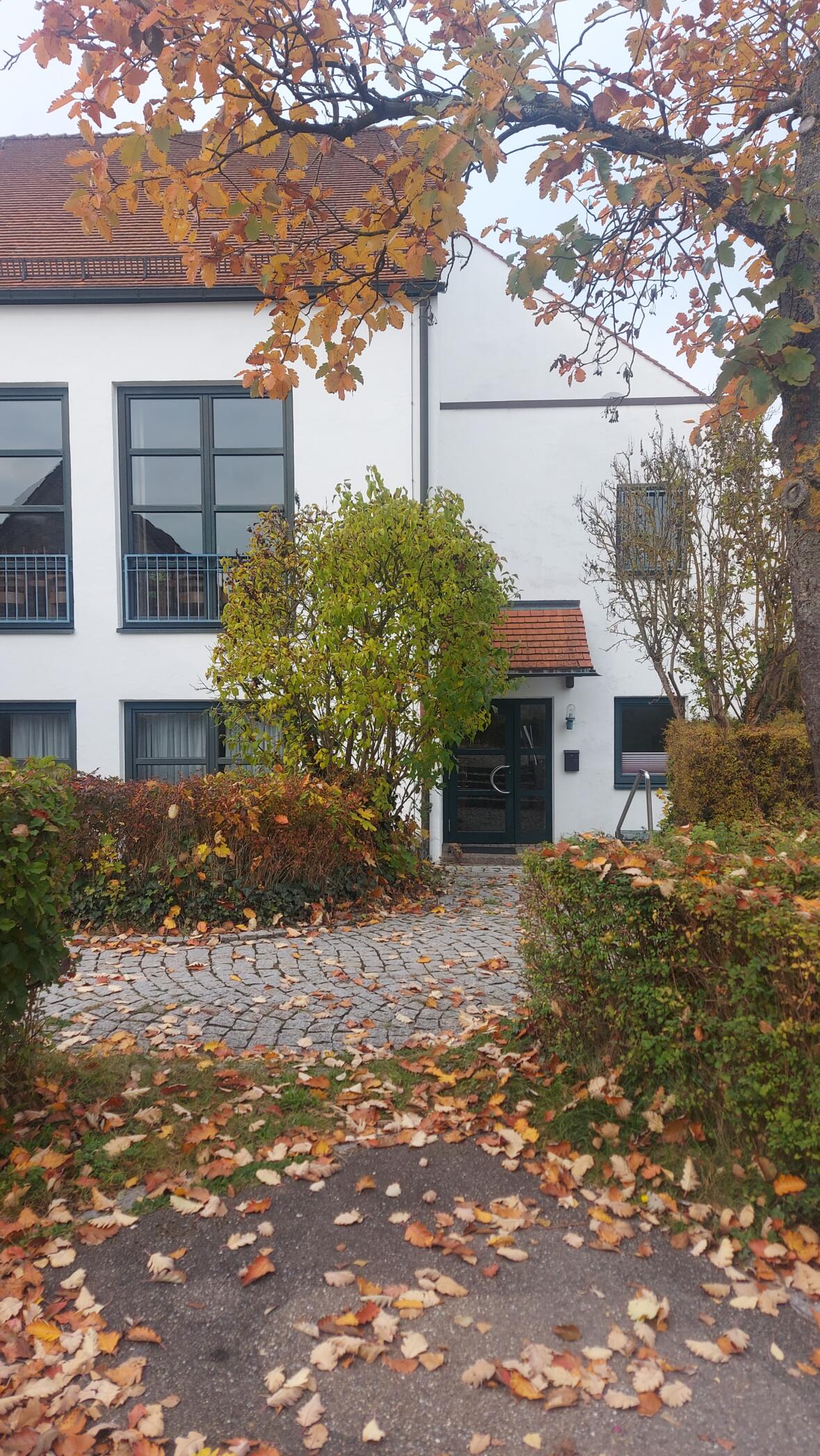 Eingang der KJG Thalfingen im Pfarrzentrum, umgeben von buntem Herbstlaub.