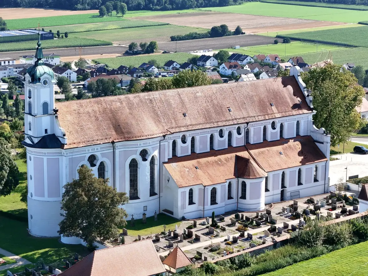 Oberelchingen Klosterkirche Luftbild Kirche mit Grabsteinanlage im Vordergrund, umgeben von Feldern und Wohnhäusern.