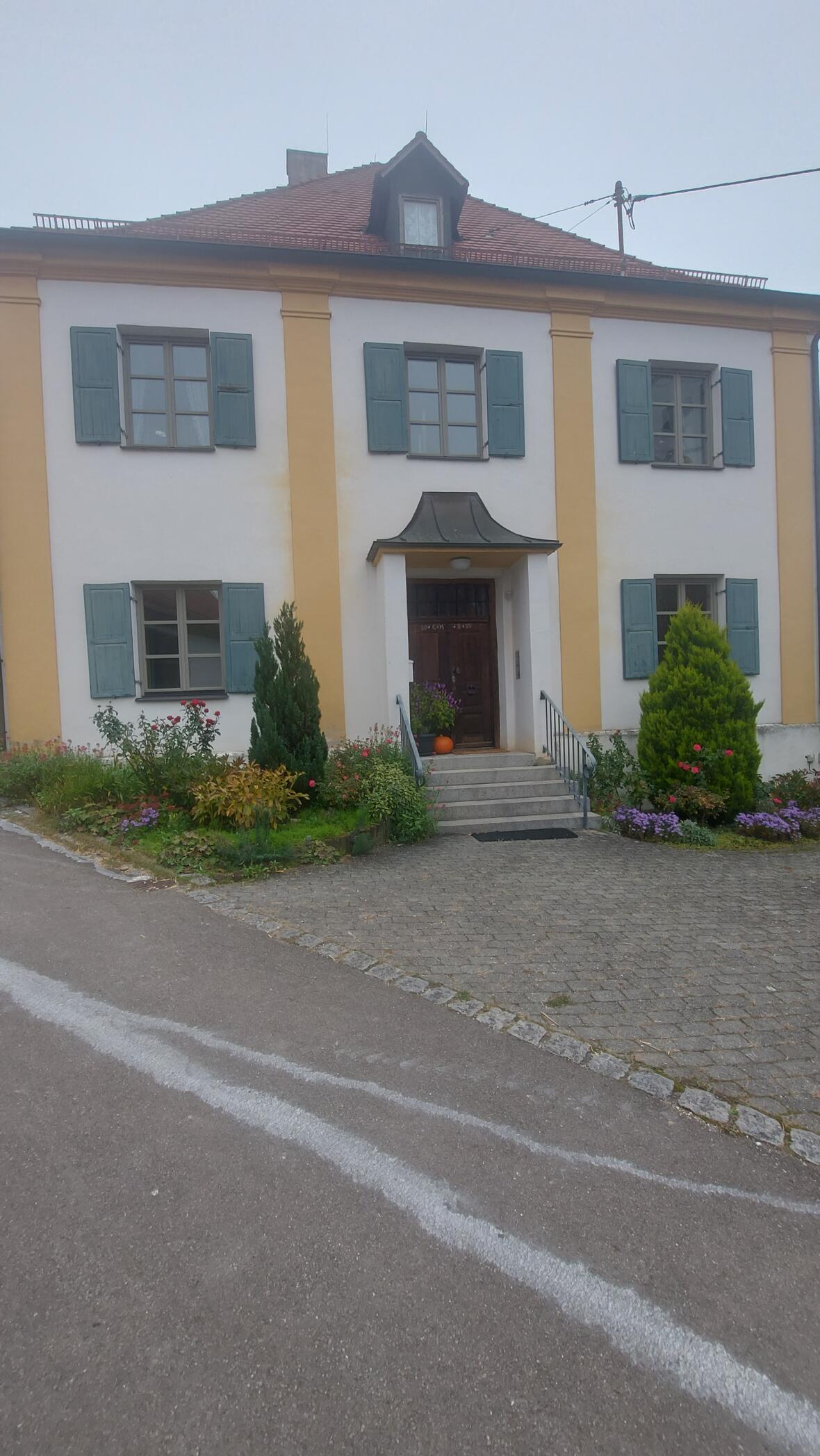 Eingang des Hauses St. Michael in Unterelchingen, umgeben von Blumen und Pflanzen.