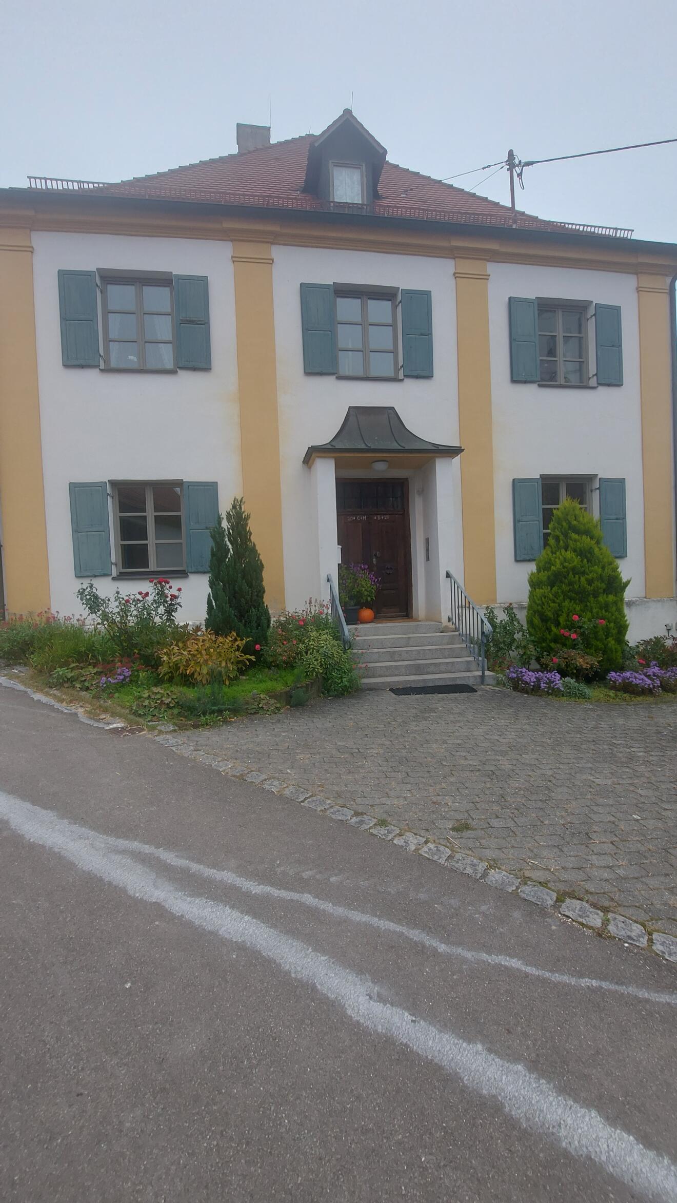 Eingang des Hauses St. Michael in Unterelchingen, umgeben von Blumen und Pflanzen.