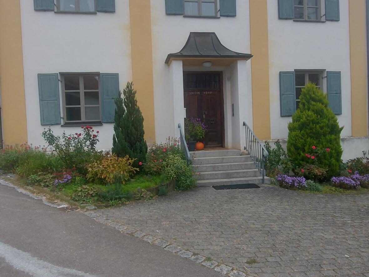 Eingang des Hauses St. Michael in Unterelchingen, umgeben von Blumen und Pflanzen.